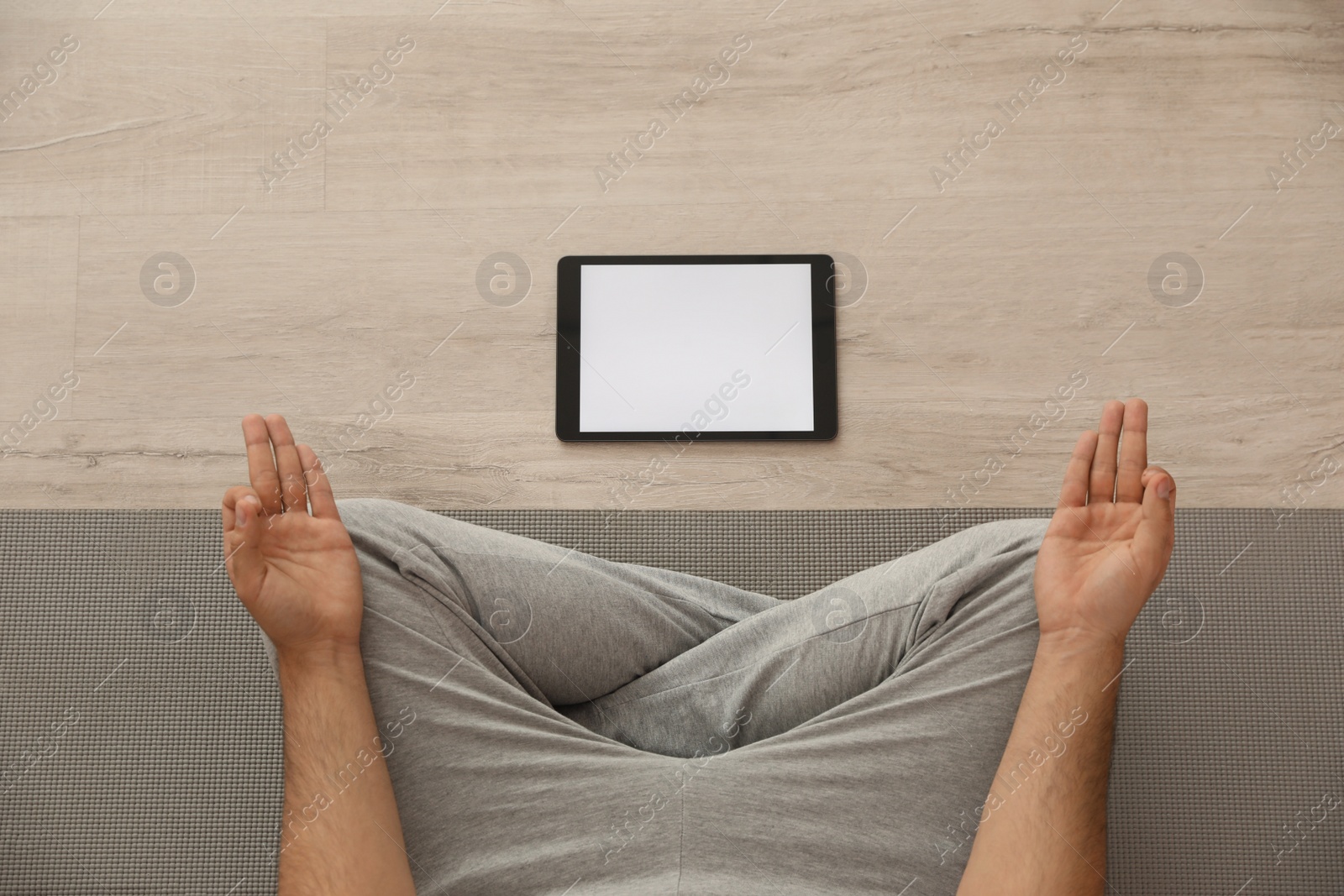 Photo of Man practicing yoga while watching online class at home during coronavirus pandemic, top view. Social distancing