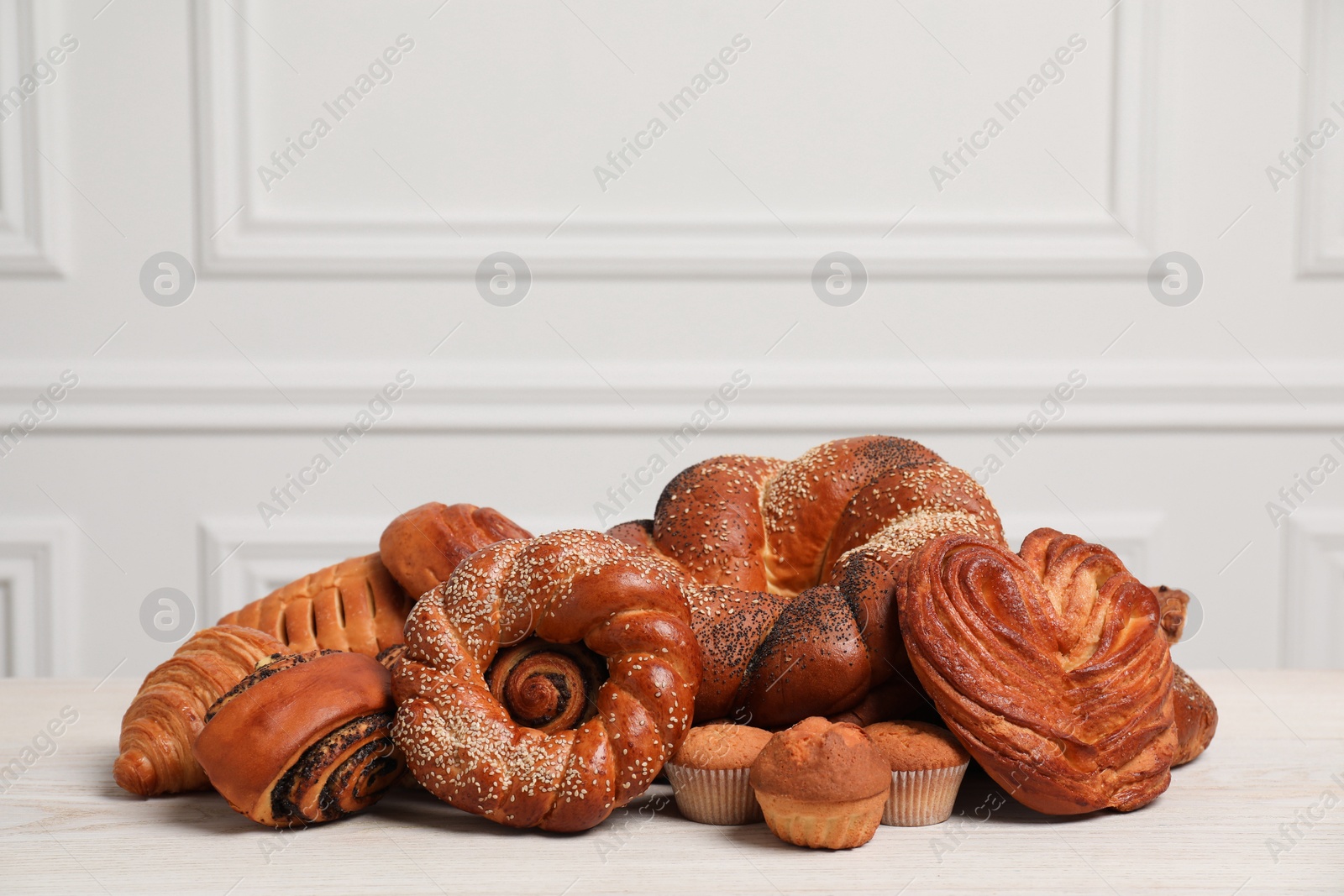 Photo of Different tasty freshly baked pastries on white wooden table, space for text