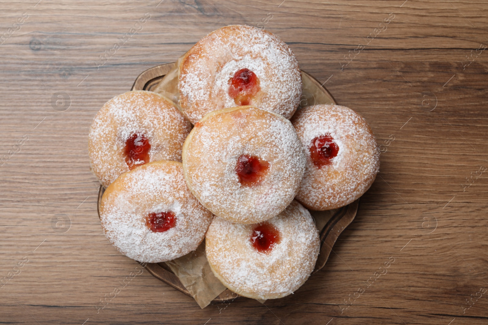 Photo of Delicious donuts with jelly and powdered sugar on wooden table, top view