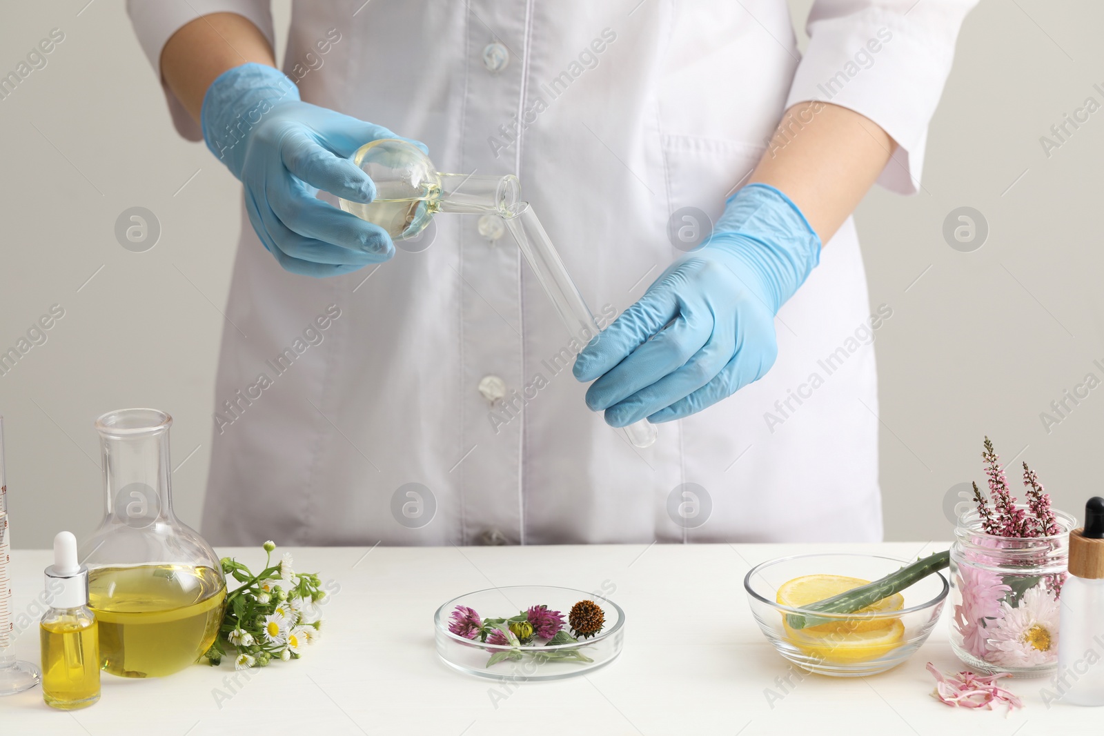 Photo of Scientist developing cosmetic oil at white table, closeup