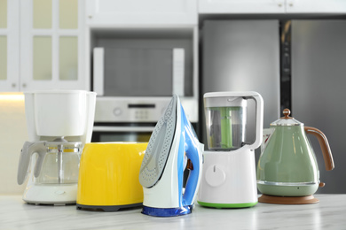 Photo of Set of modern home appliances on white marble table in kitchen