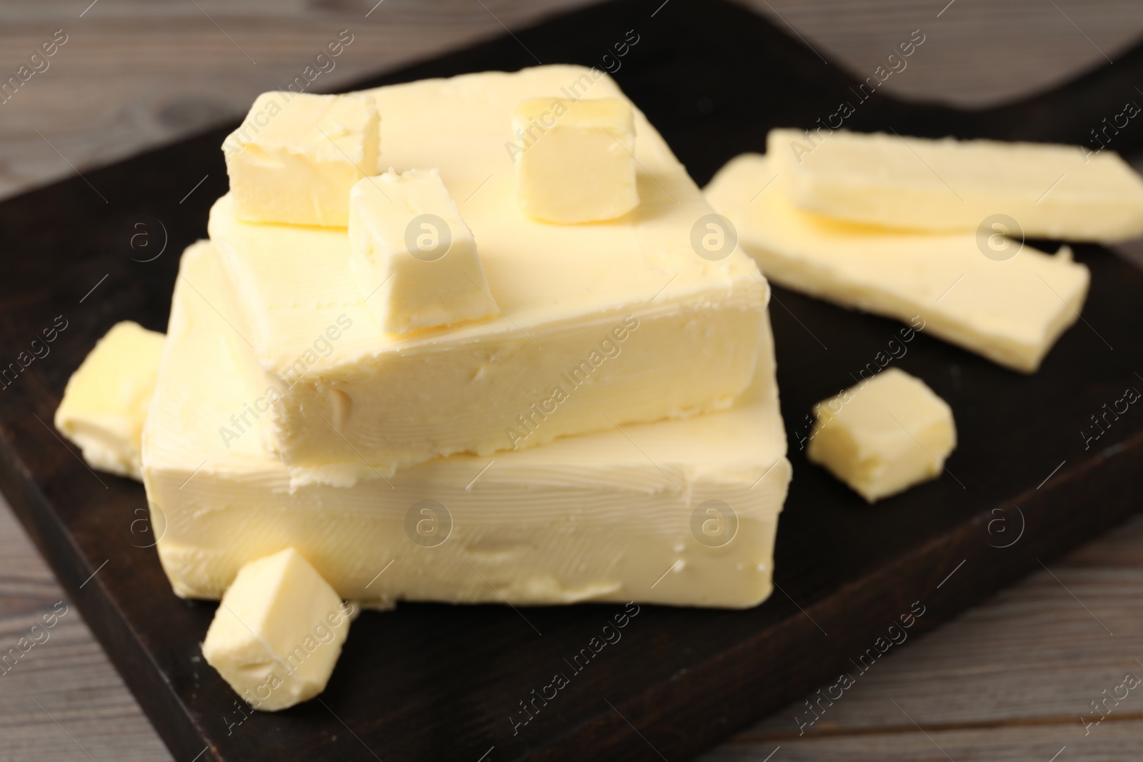 Photo of Pieces of tasty butter on wooden table, closeup