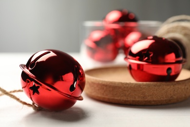 Red sleigh bell with rope on white table, closeup