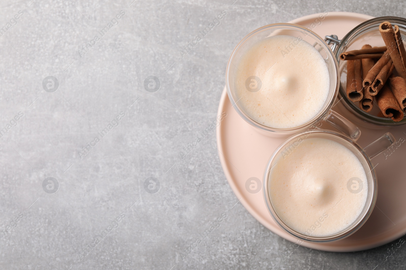 Photo of Delicious eggnog with cinnamon on light grey table, flat lay. Space for text