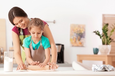 Photo of Mother and her daughter preparing dough at table in kitchen