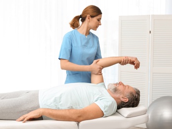 Photo of Physiotherapist working with patient in clinic. Rehabilitation therapy