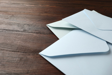 Photo of White paper envelopes on wooden table, closeup. Space for text