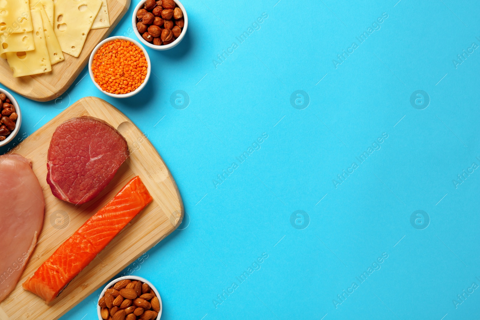 Photo of Different fresh products on light blue background, flat lay and space for text. Sources of essential amino acids