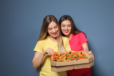 Photo of Attractive young women with delicious pizza on color background