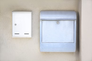 Photo of White metal letter boxes on beige wall