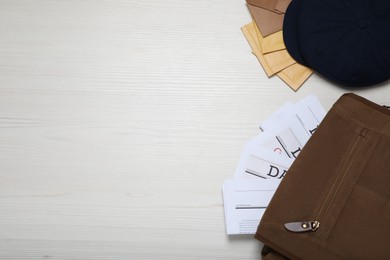 Photo of Postman hat, bag, newspapers and mails on white wooden table, flat lay. Space for text