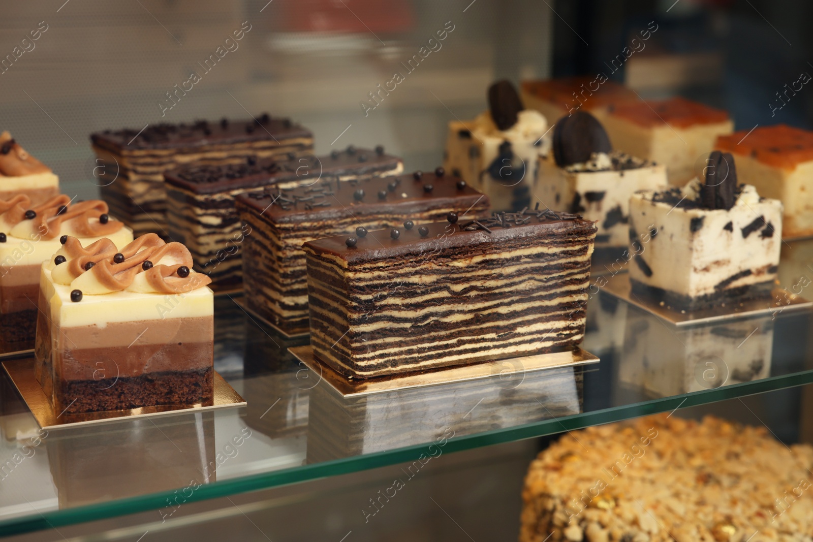 Photo of Showcase with different tasty desserts in store, closeup