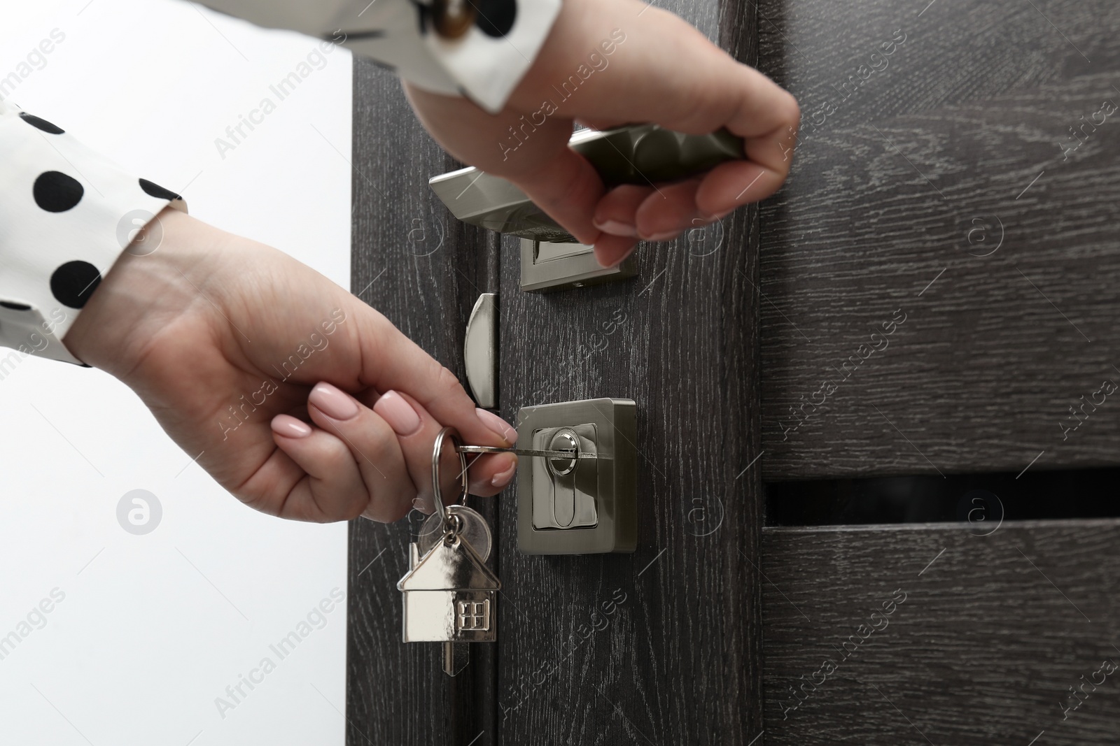 Photo of Woman unlocking door with key, closeup view