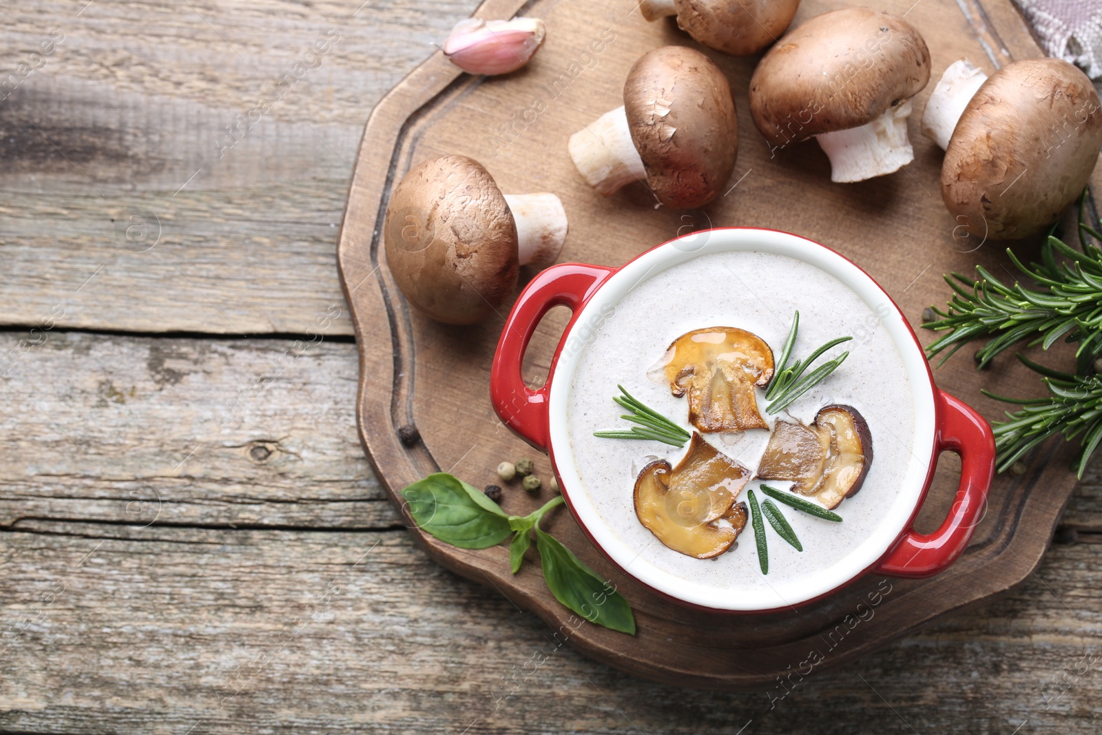 Photo of Delicious homemade mushroom soup in ceramic pot and fresh ingredients on wooden table, flat lay. Space for text