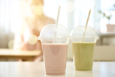 Photo of Tasty fresh milk shakes in plastic cups in cafe