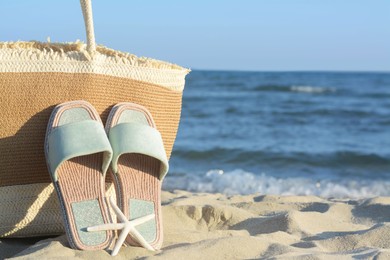 Stylish bag, slippers and dry starfish on sandy beach near sea, closeup. Space for text