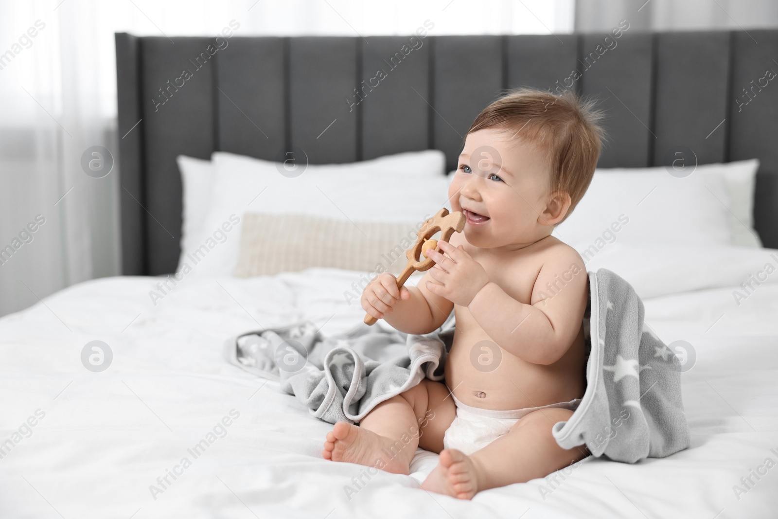 Photo of Happy baby boy with blanket and rattle sitting on bed at home. Space for text