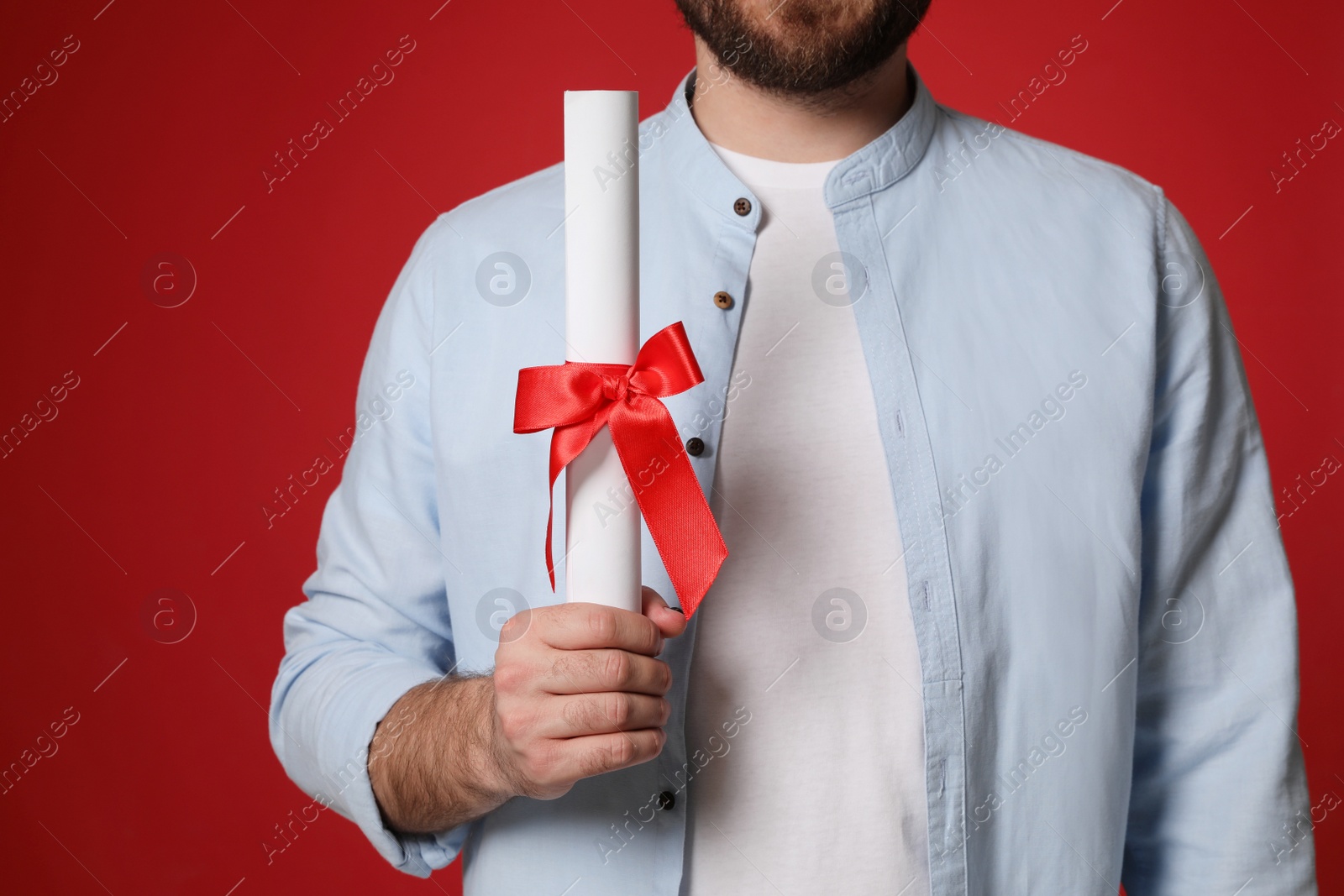 Photo of Student with diploma on red background, closeup