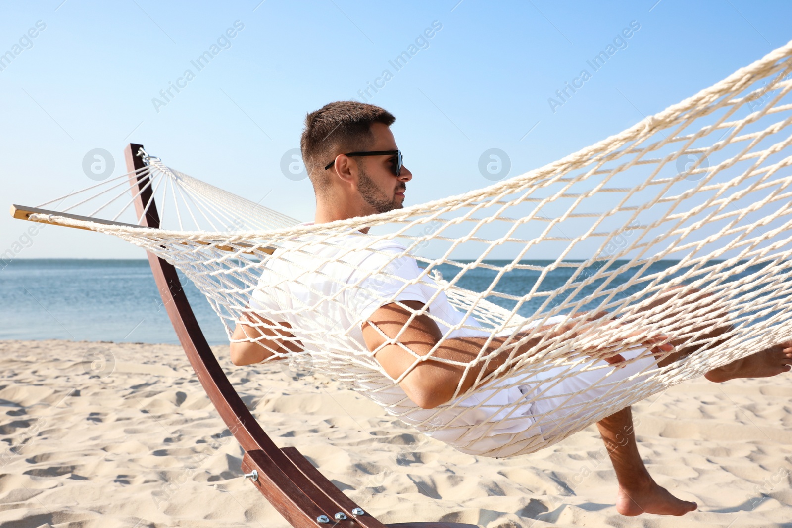 Photo of Young man relaxing in hammock on beach