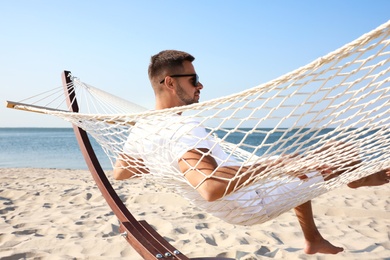 Young man relaxing in hammock on beach