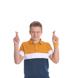 Handsome teenage boy crossing his fingers on white background