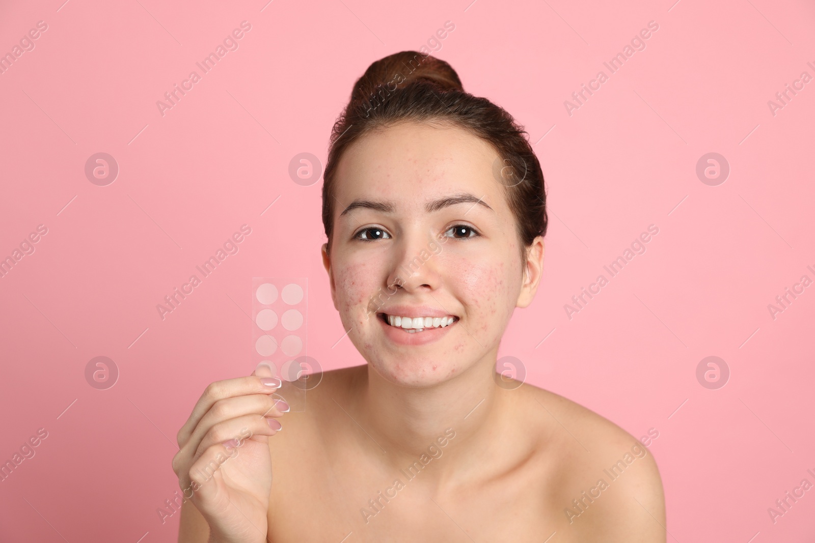 Photo of Teen girl holding acne healing patches on light pink background