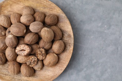 Photo of Wooden board with nutmegs on light grey table. Space for text