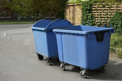 Photo of Two open blue dumpsters with wheels on city street