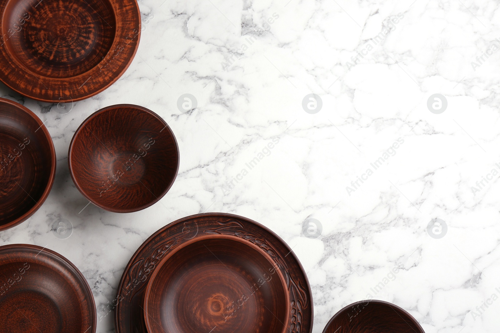 Photo of Set of clay utensils on white marble table, flat lay. Space for text