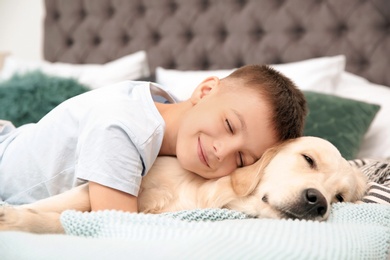 Cute little child with his pet on bed at home