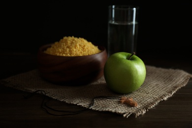 Photo of Millet, apple, water and crucifix on wooden table. Great Lent season