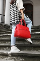 Photo of Young woman with stylish bag on stairs outdoors, closeup