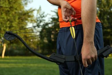 Photo of Man with bow and arrow practicing archery in park, closeup