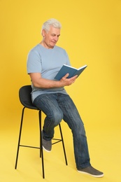 Photo of Senior man reading book on color background