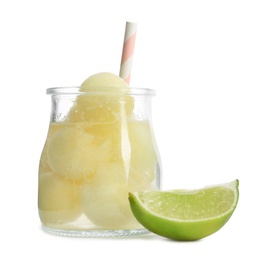 Photo of Glass jar of melon ball cocktail and lime on white background