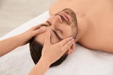 Photo of Handsome man receiving face massage in spa salon