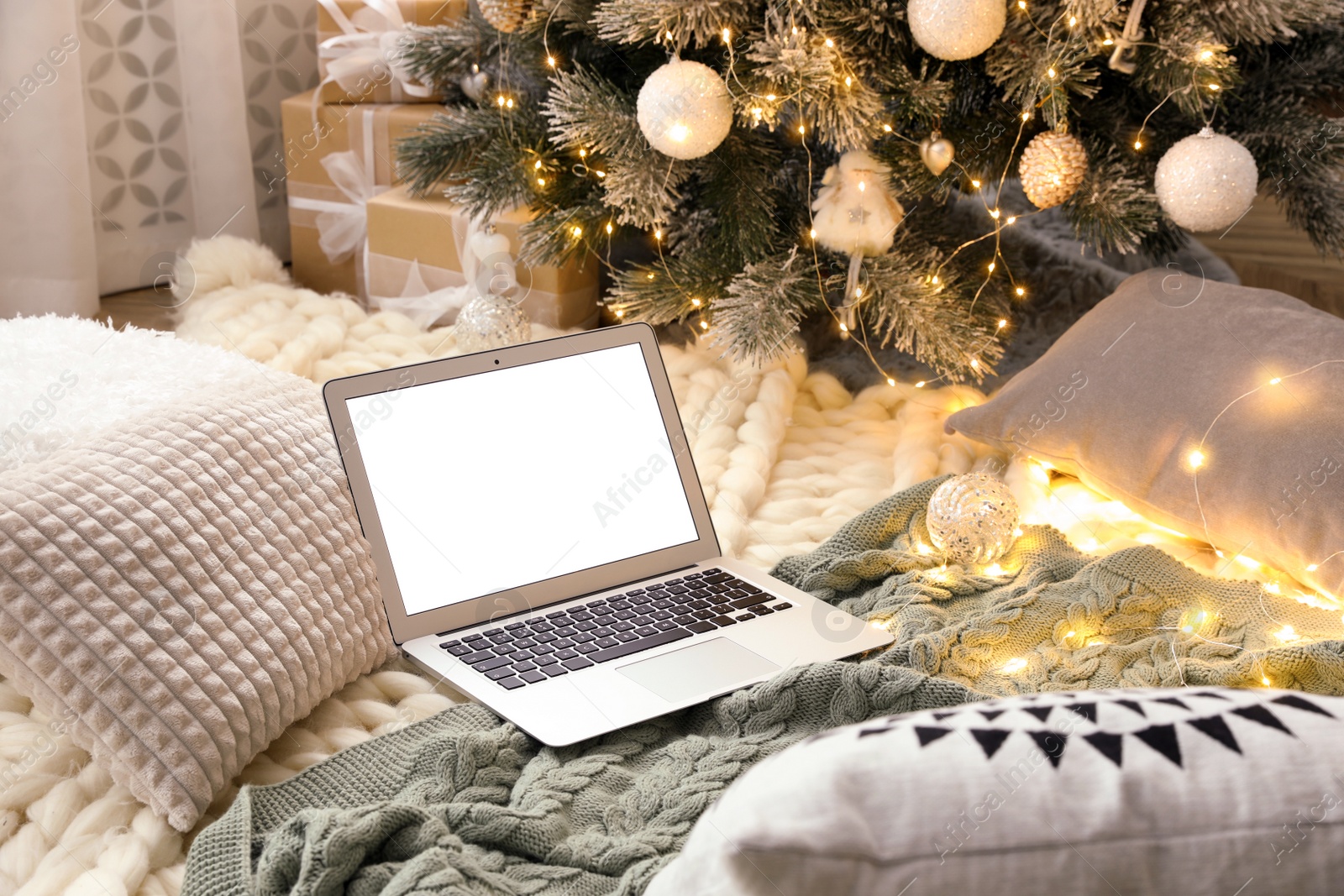 Photo of Modern laptop on plaid near Christmas tree