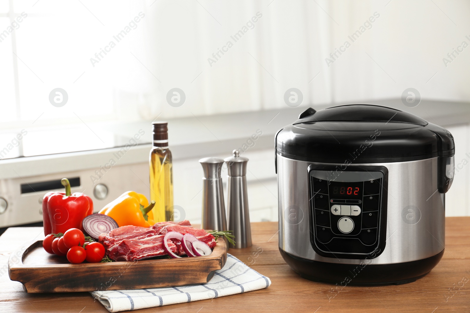 Photo of Modern multi cooker and products on wooden table in kitchen