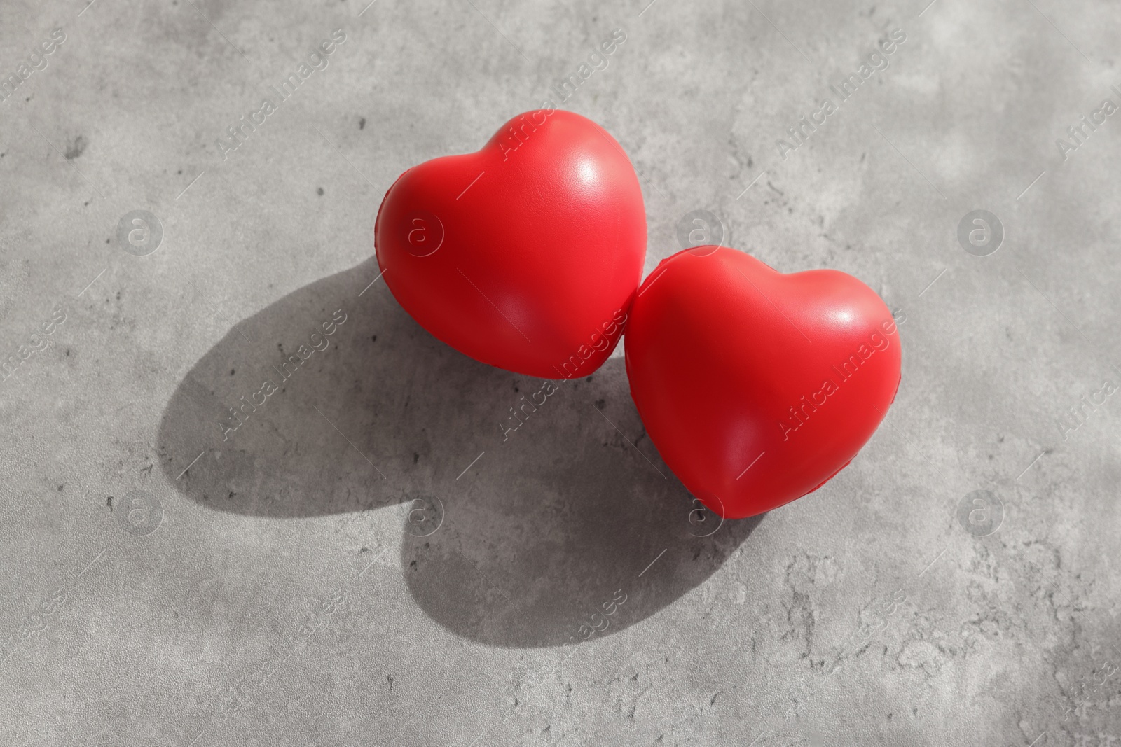 Photo of Two decorative hearts on gray textured table, above view