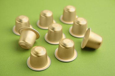 Photo of Many coffee capsules on green background, closeup