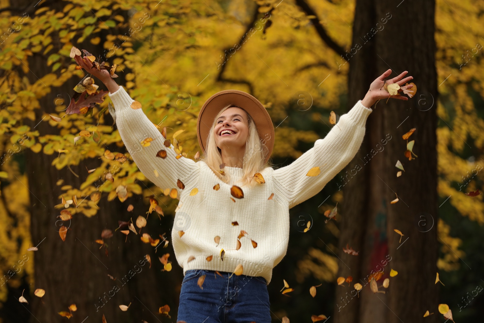 Photo of Autumn vibes. Happy woman throwing leaves up in park