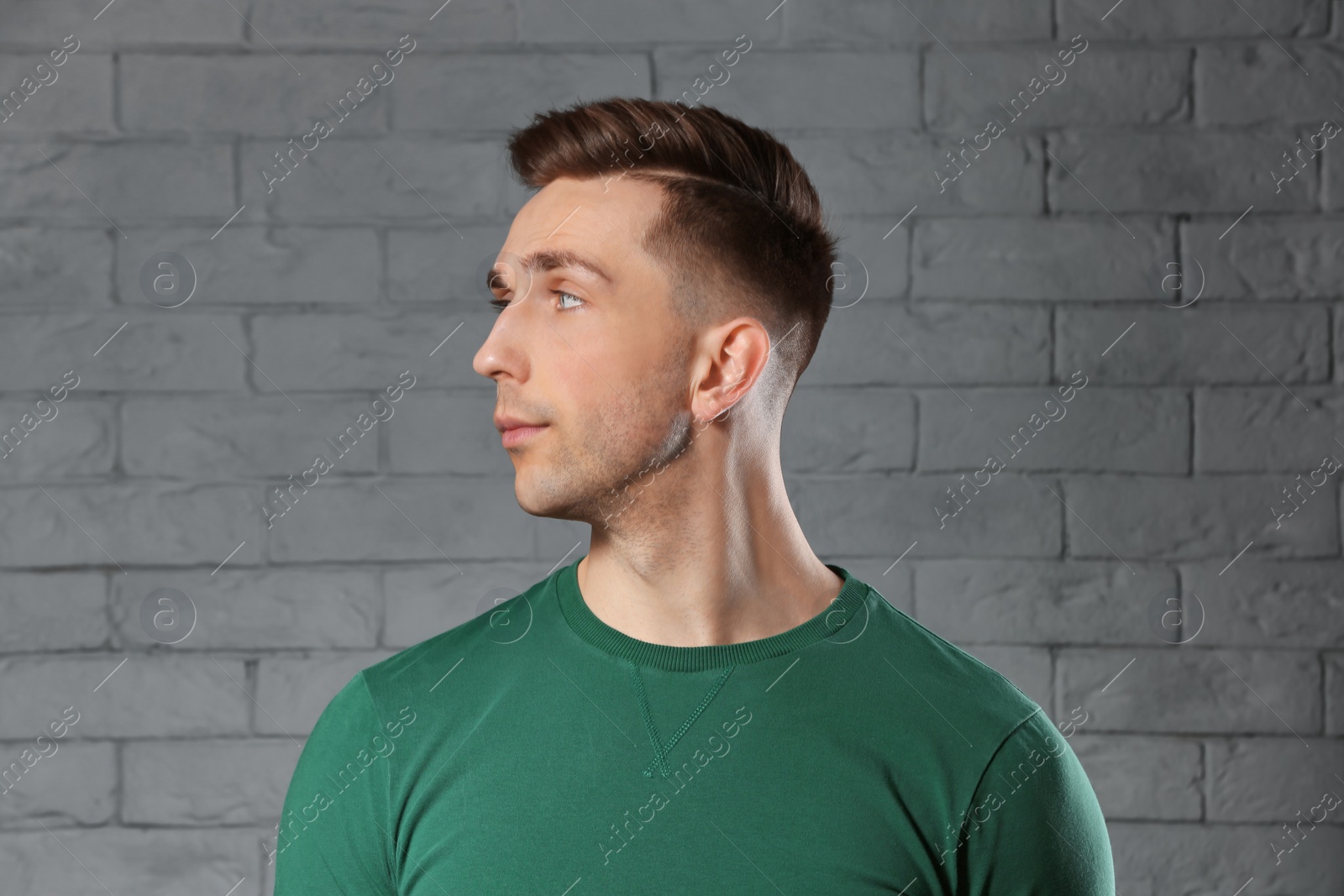 Photo of Portrait of young man with beautiful hair on brick wall background