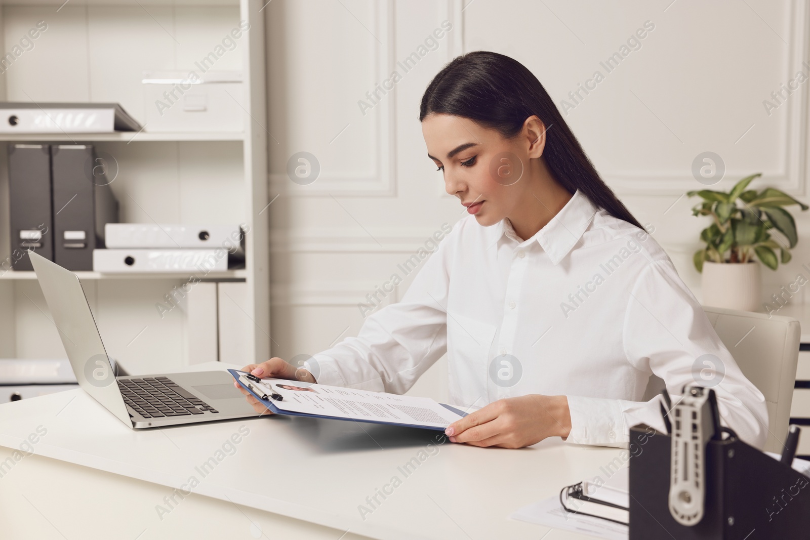 Photo of Human resources manager reading applicant's resume at white table in office