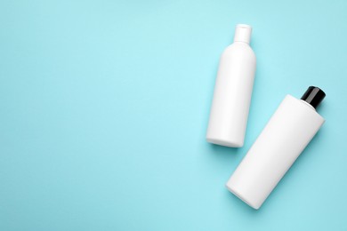 Photo of Bottles of shampoo on light blue background, flat lay. Space for text
