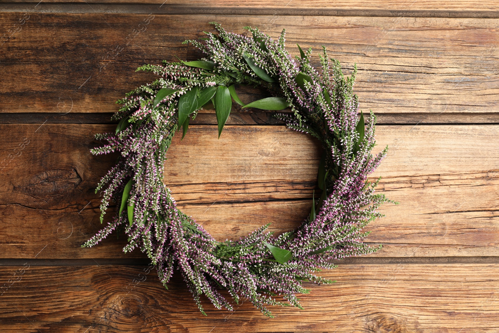 Photo of Beautiful autumnal wreath with heather flowers on wooden background, top view. Space for text