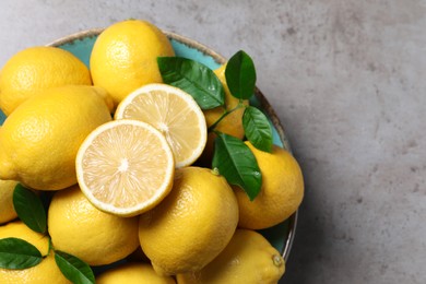 Photo of Fresh lemons and green leaves on grey table, top view