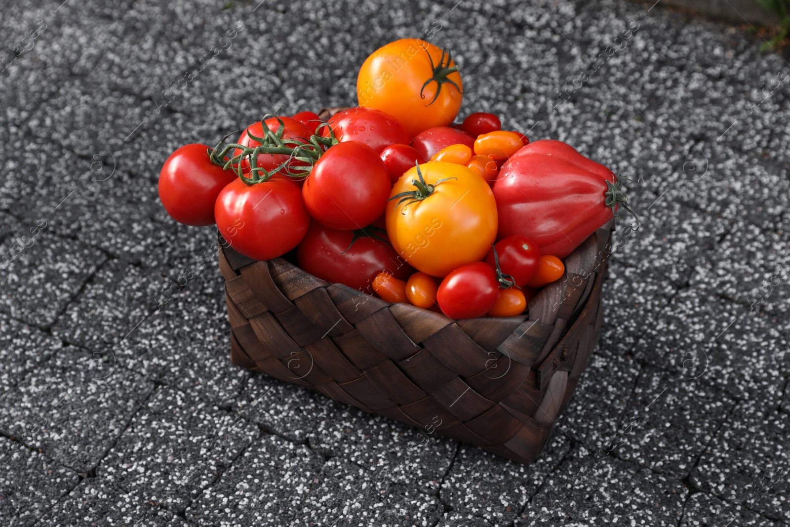 Photo of Basket with fresh tomatoes on stone surface