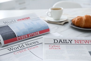 Newspapers with headline CYBER ATTACK on table indoors