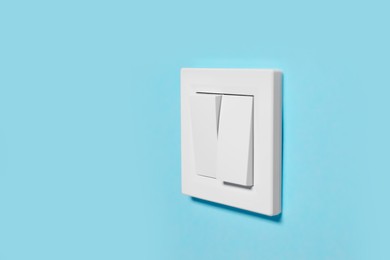 Photo of Modern plastic light switch on blue wall, space for text
