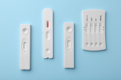 Photo of Different disposable express tests on light blue background, flat lay